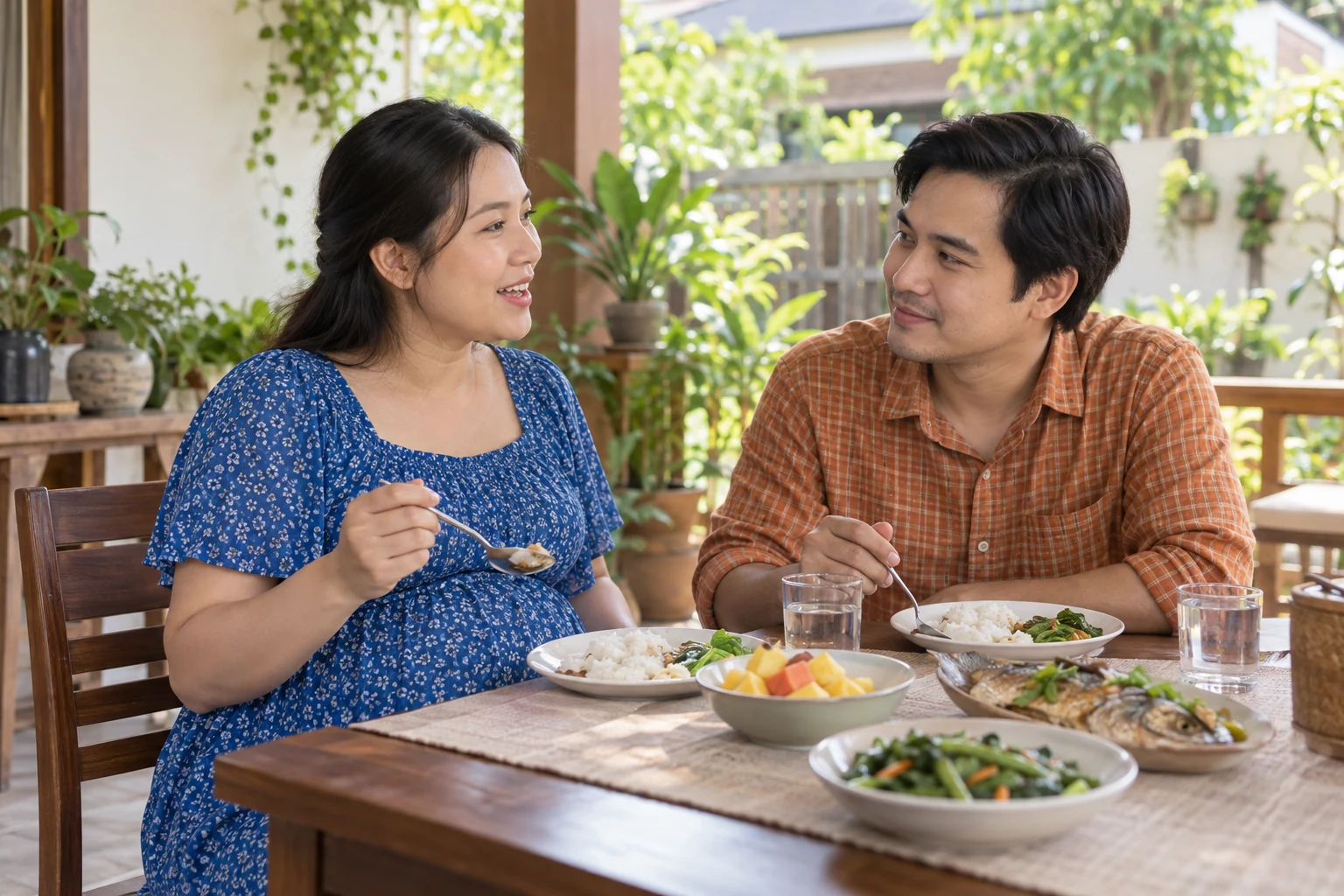 หญิงตั้งครรภ์ชาวไทยกินข้าวและพูดคุยกับคู่ของเธอที่โต๊ะอาหารบริเวณบ้าน